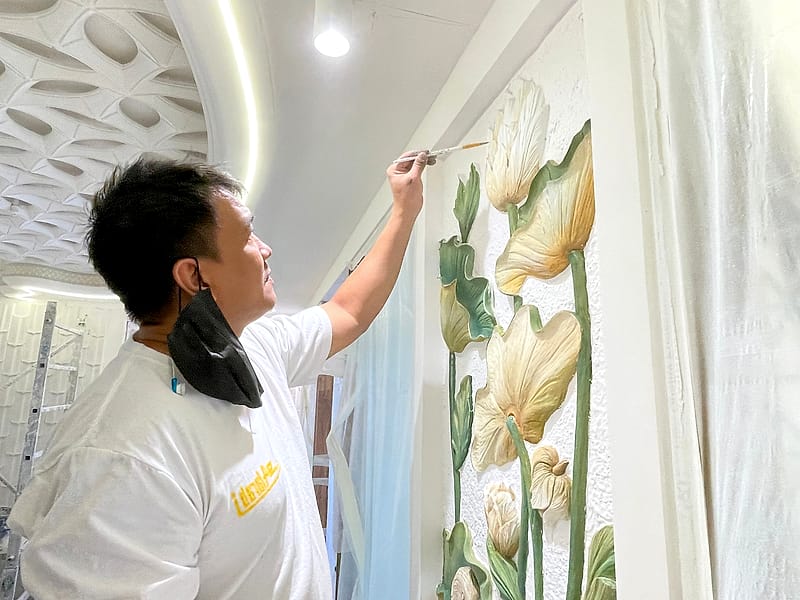 فنانٌ من العربي يرسمُ زخرفةً نباتيةً منحوتةً بالفرشاة
